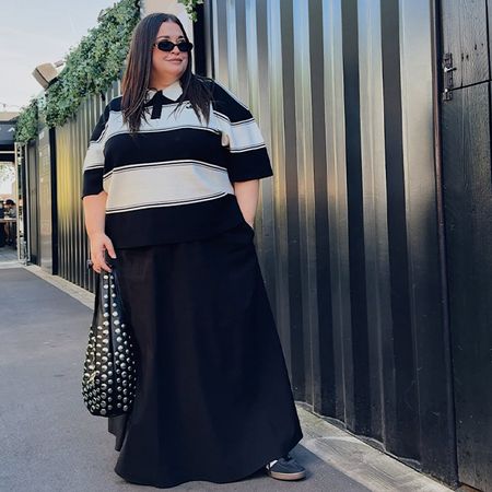 Danielle wears t-shirt with black skirt and studded bag with sambas. 