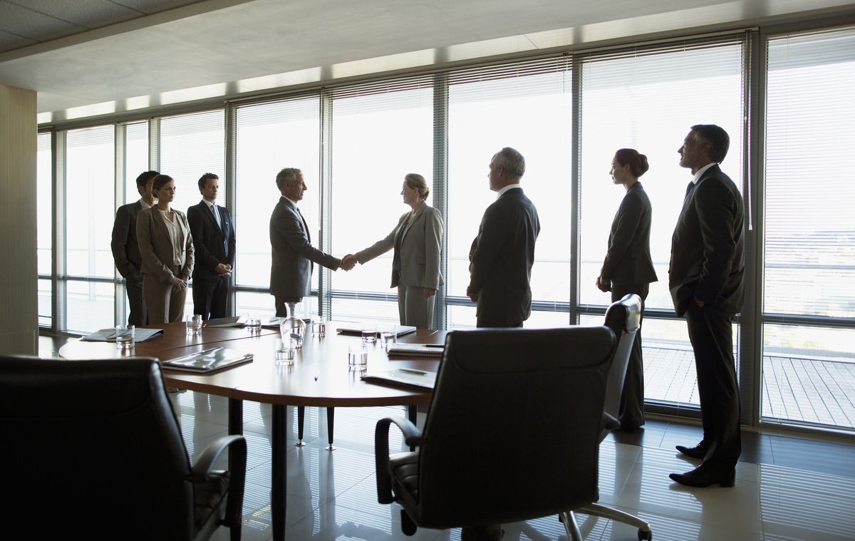 Group of people in office business meeting with two representatives shaking hands