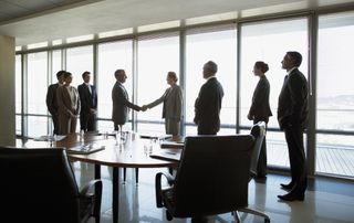 Group of people in office business meeting with two representatives shaking hands