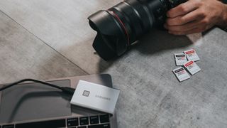 digital camera on floor alongside external hard drive and SD cards