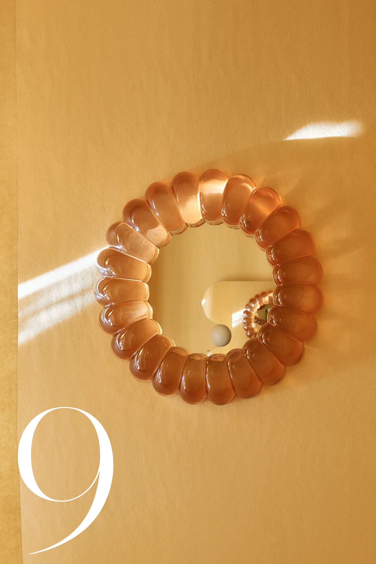 round mirror that look slike jelly hanging on a yellow wall