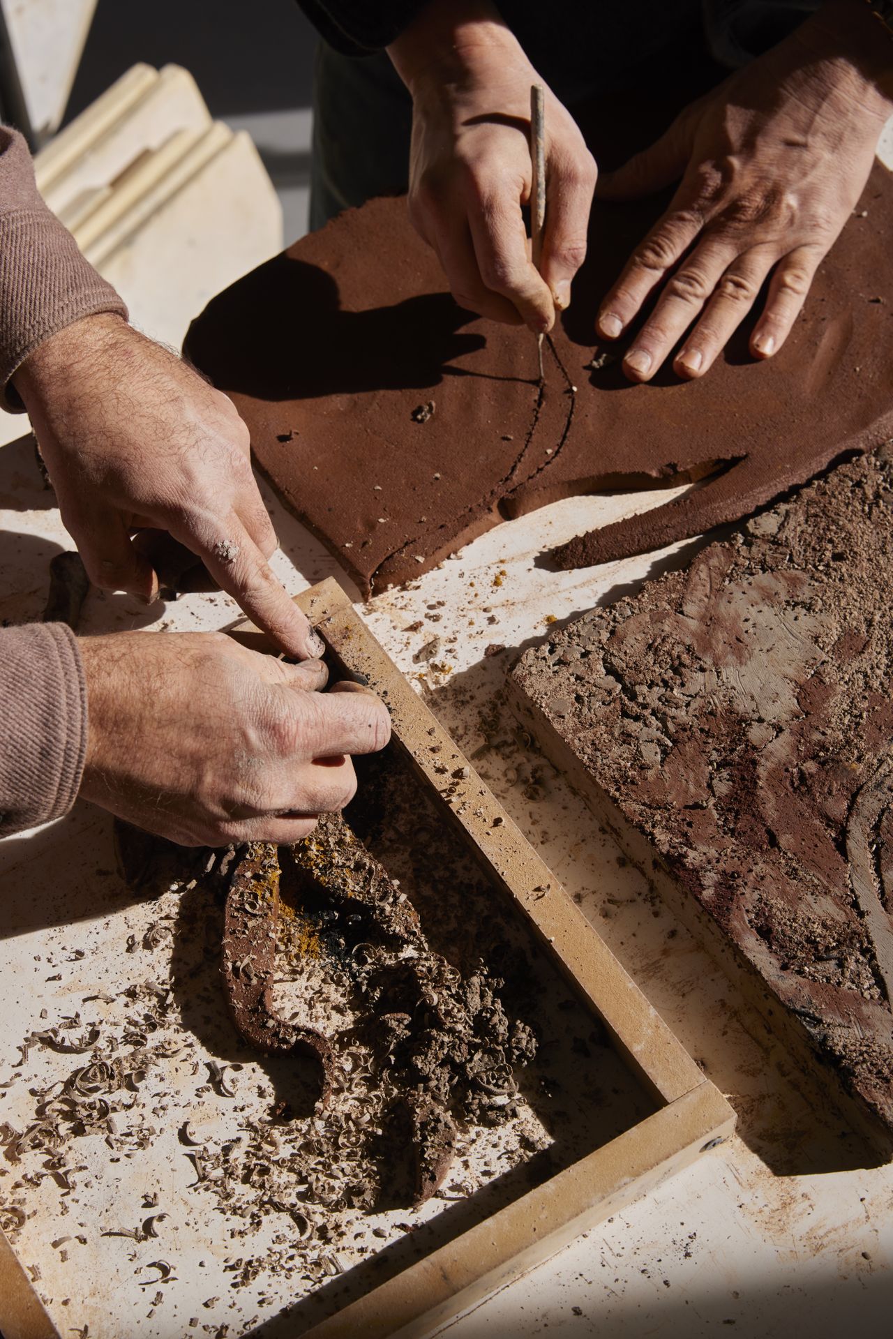 Two people work on dirt-made artworks.
