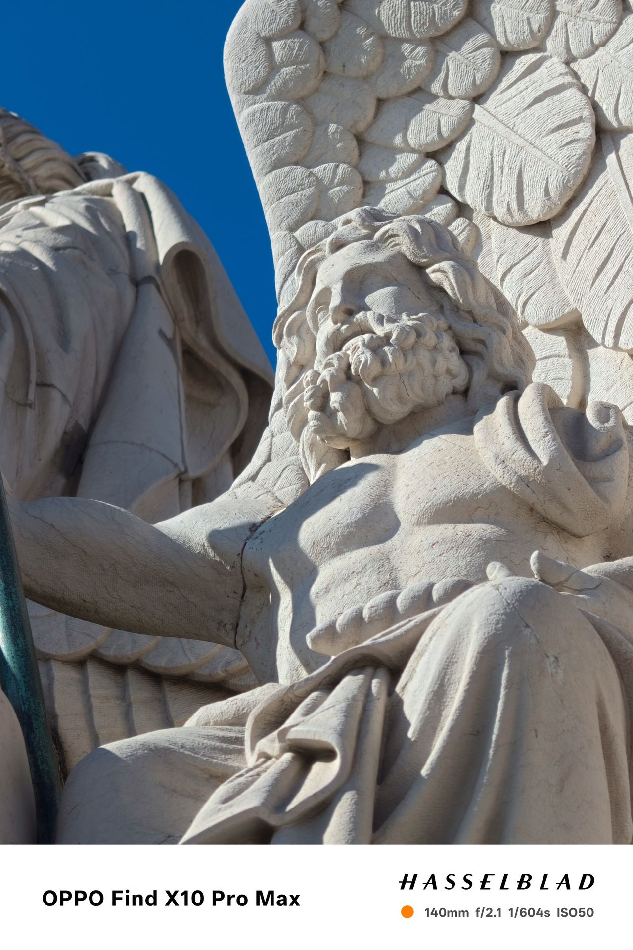 Close-up of an ornate white stone bearded figure carved into a monument.