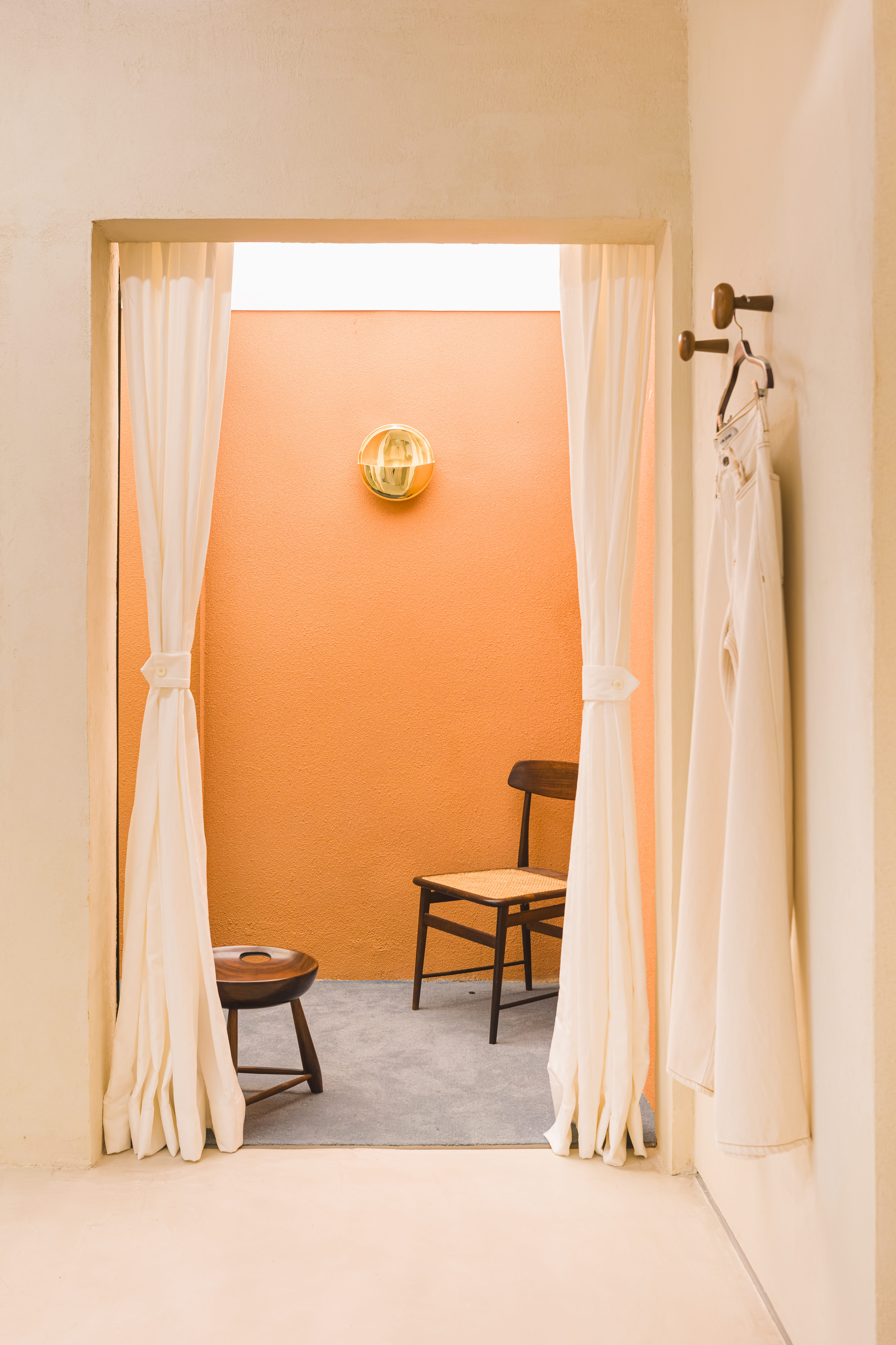 A creatively designed denim boutique features a cream-washed brick outdoor with a facade that reads "The best jeans." and buttery interiors punctuated by golden accents and wooden furniture.
