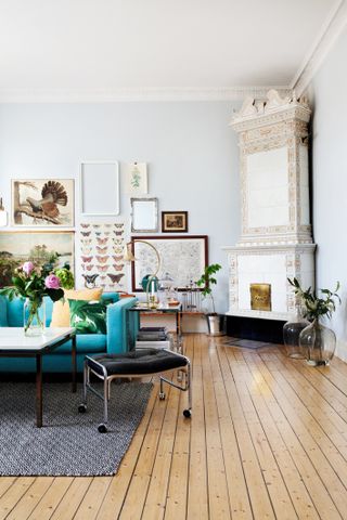 living room with original floor, gallery wall comprised of an eclectoce combination of images and bright blue sofa