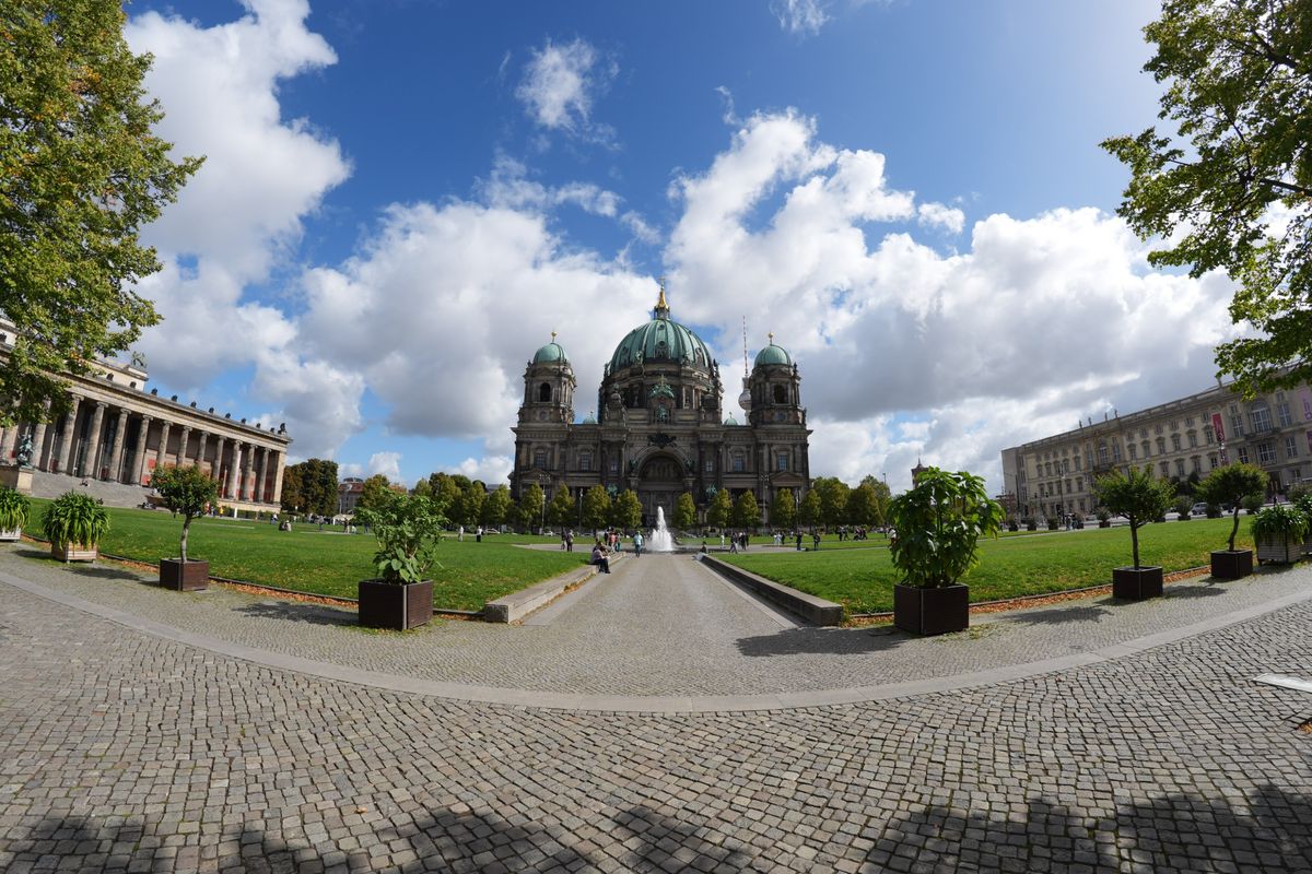 Wide-angle view of Berlin Cathedral and the surrounding Lustgarten on a bright, partly cloudy day.