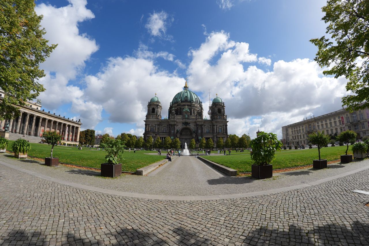 Wide-angle view of Berlin Cathedral and the surrounding Lustgarten on a bright, partly cloudy day.
