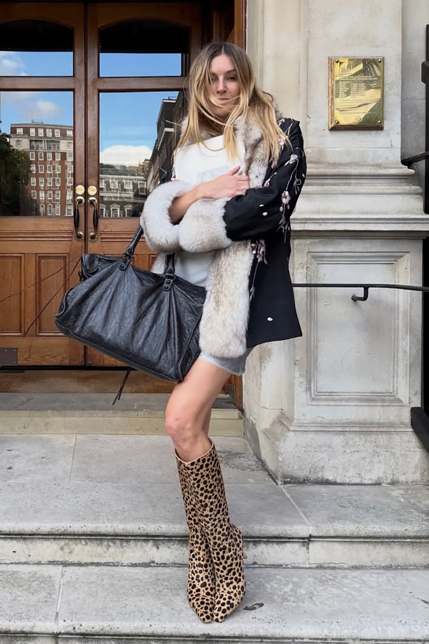 a woman wearing a black jacket, black leather bag, and animal print boots