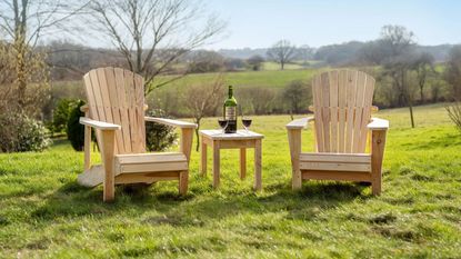 A pair of wooden Adirondack chairs on a grass lawn