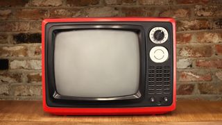 An old TV in front of a brick wall