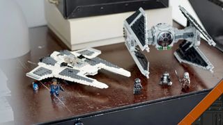 Lego Mandalorian Fang Fighter and TIE Interceptor with minifigures on a wooden surface