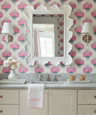 bathroom with hot pink floral patterned wallpaper, white mirror, light neutral vanity and marble countertop