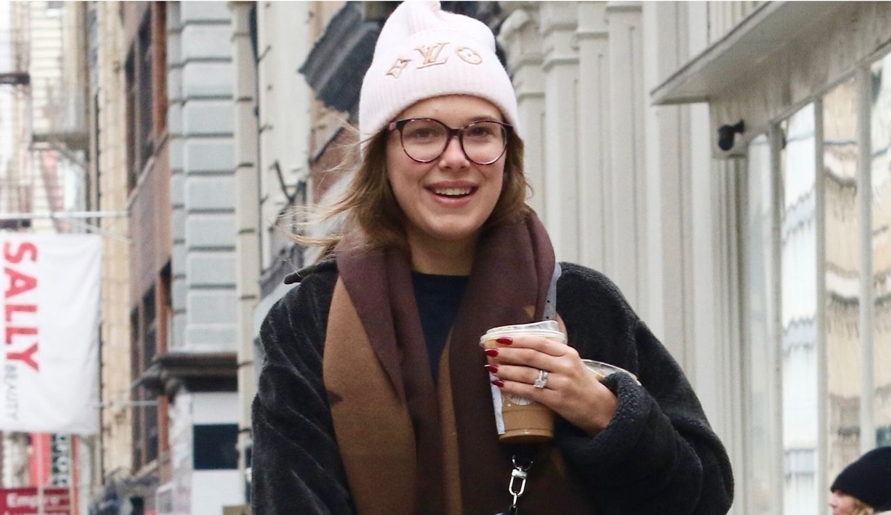 Millie Bobby Brown wears a black teddy coat with a louis vuitton cap and scarf matching her poodle in new york city