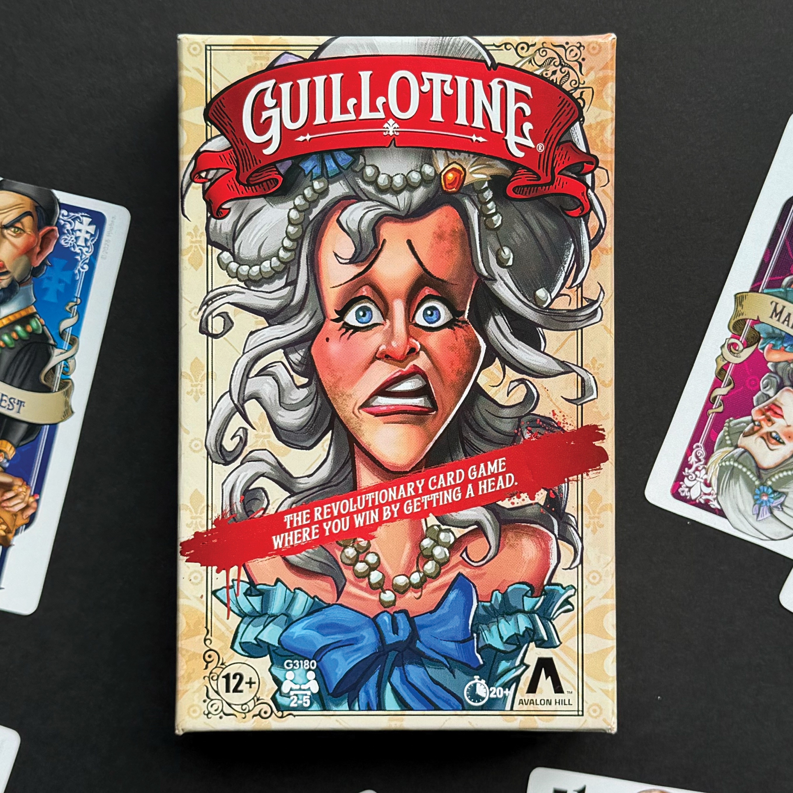 Guillotine box, cards, and prop on a dark background