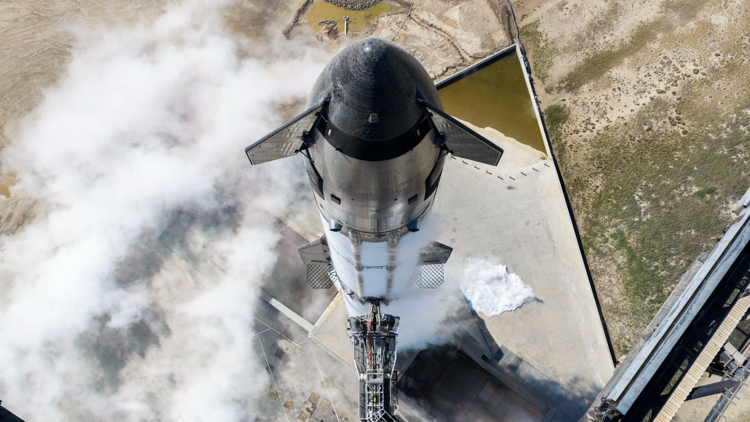 drone photo looking down at a big silver rocket on a launch pad