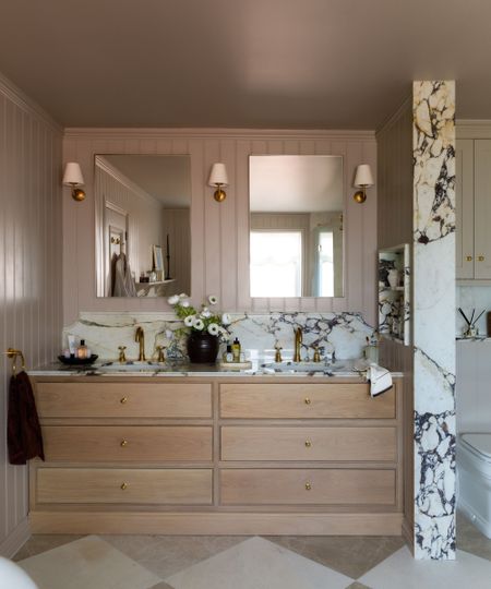 Bathroom with Elephant's Breath by Farrow & Ball painted walls, a double-sink vanity unit with marble countertop, wooden drawers built in underneath and two mirrors with sconces on either side.