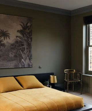 Bedroom painted in dark green/gray with mustard yellow bedding