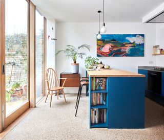 Blue kitchen island in open-plan extension with corner sliding wooden doors