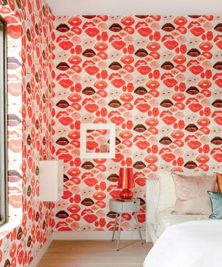 bedroom with wallpaper covered in red lips and red lamp on side table