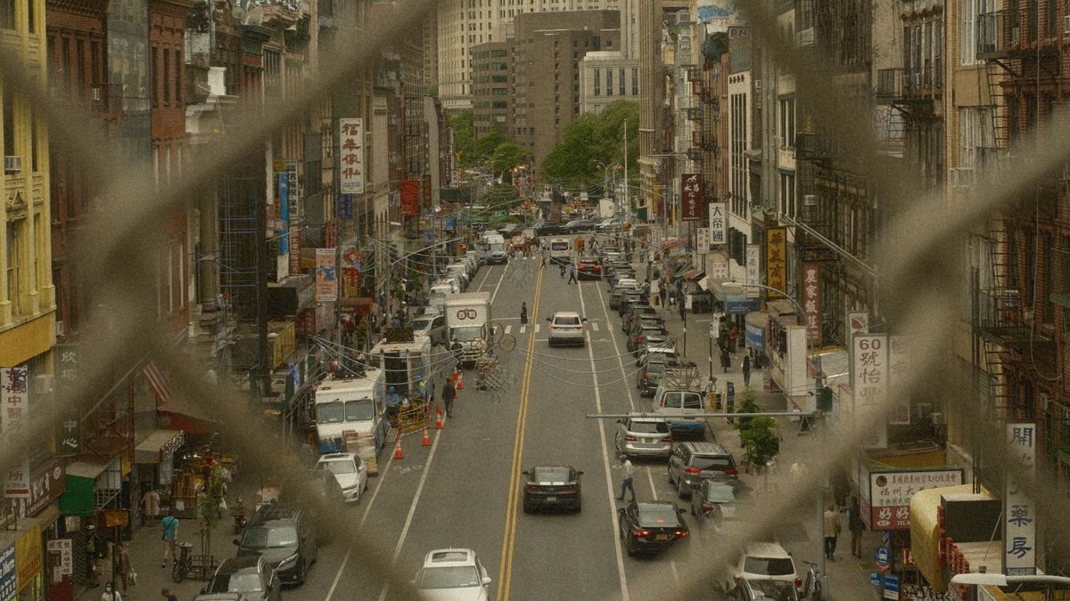 A busy street in New York City seen through a metal fence