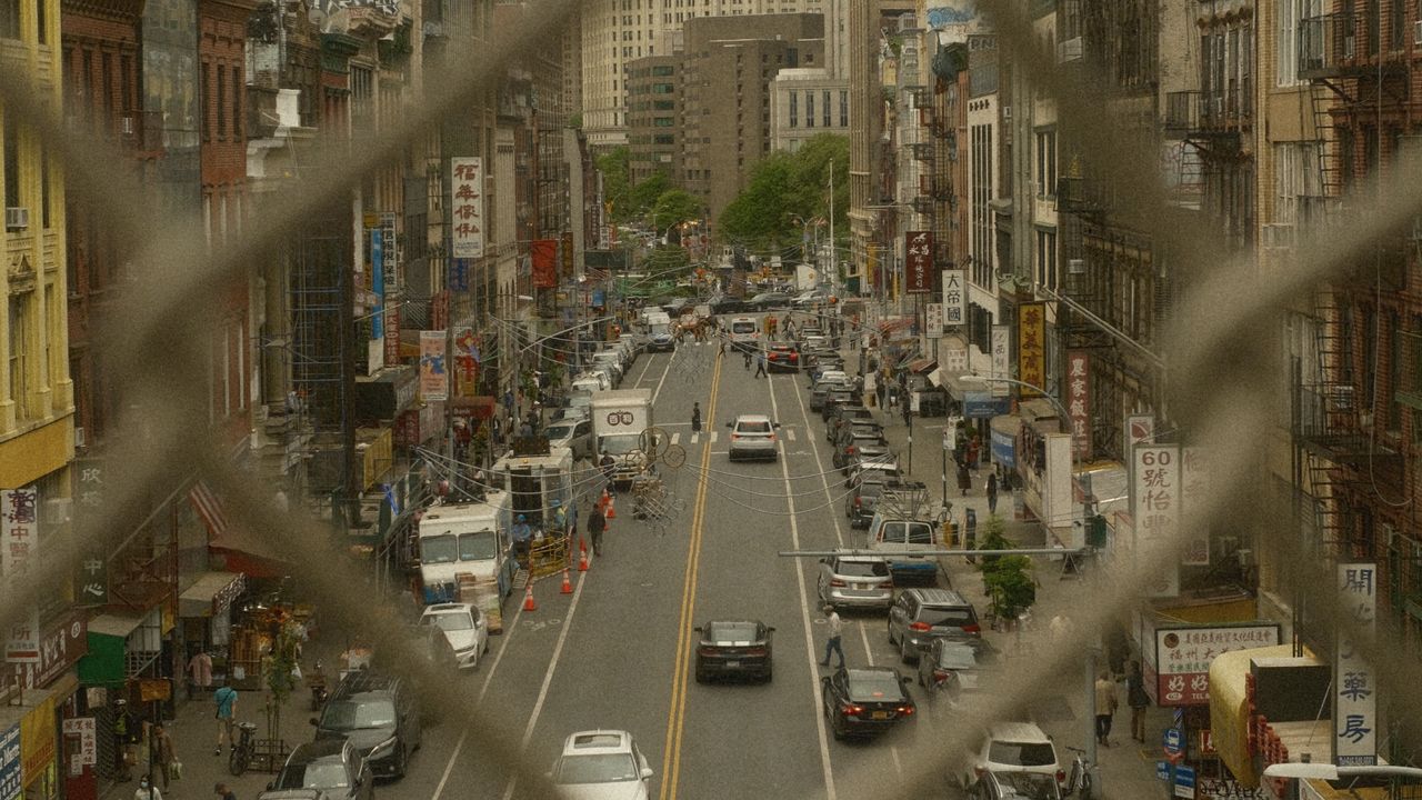 A busy street in New York City seen through a metal fence
