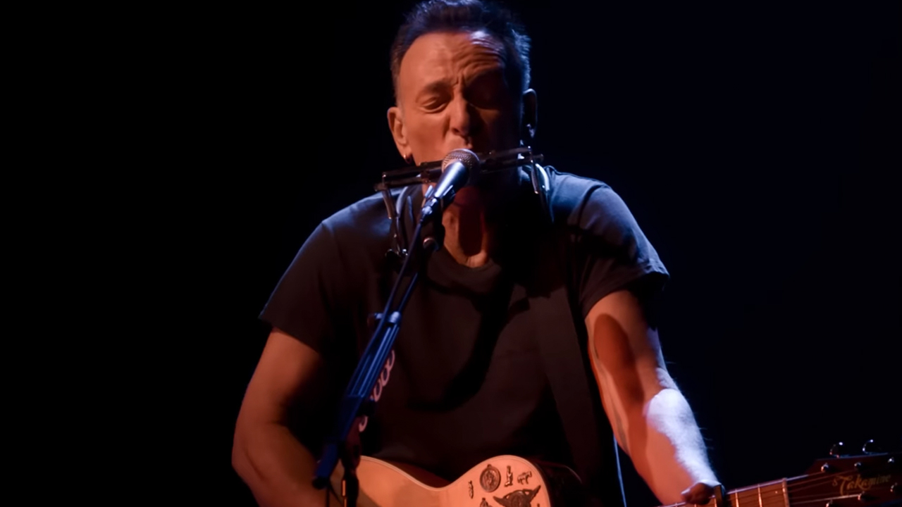 Bruce Springsteen singing intensely and playing guitar and harmonica