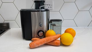 The Bagotte DB-001 juicer on a kitchen countertop next to some oranges and carrots ready to be juiced