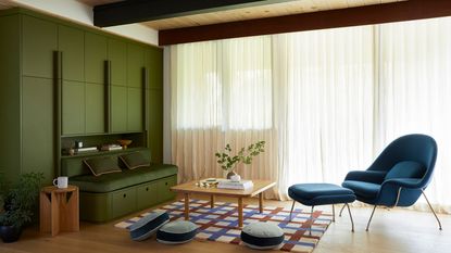 A study room with wooden furniture and earthy green walls and a blue accent chair