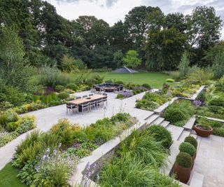 A beautifully landscaped garden with tiered planting beds and seating area
