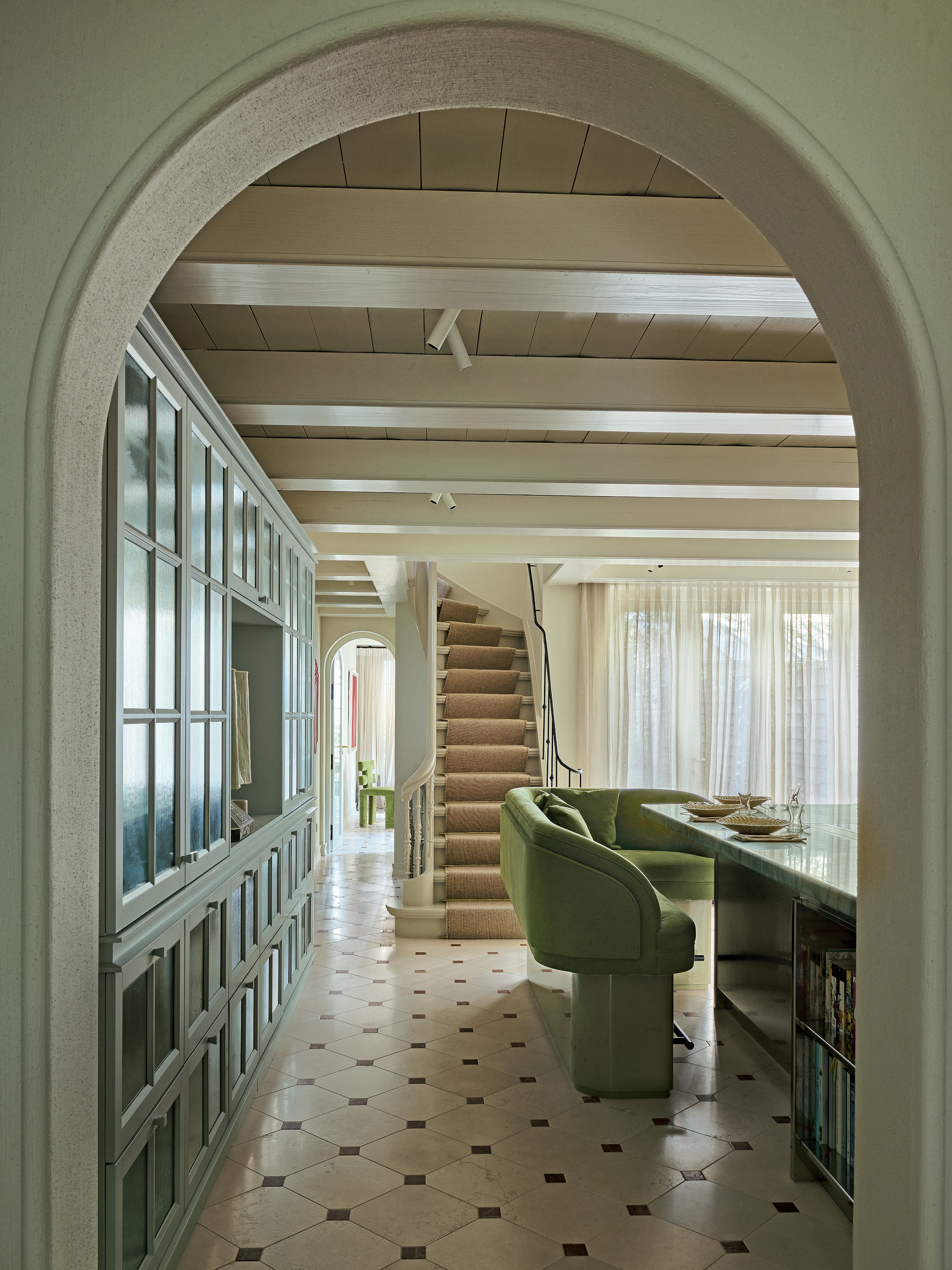 Kitchen with pale blue cabinetry and green upholstered banquette seating around island