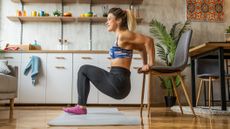 Woman exercising at home, performing dips using a chair as support