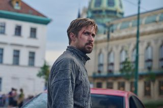 ryan gosling with blood on his forehead standing on a european street in a still from the movie the gray man