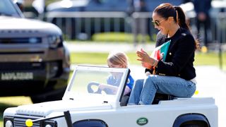 Meghan Markle in a toy car with a child