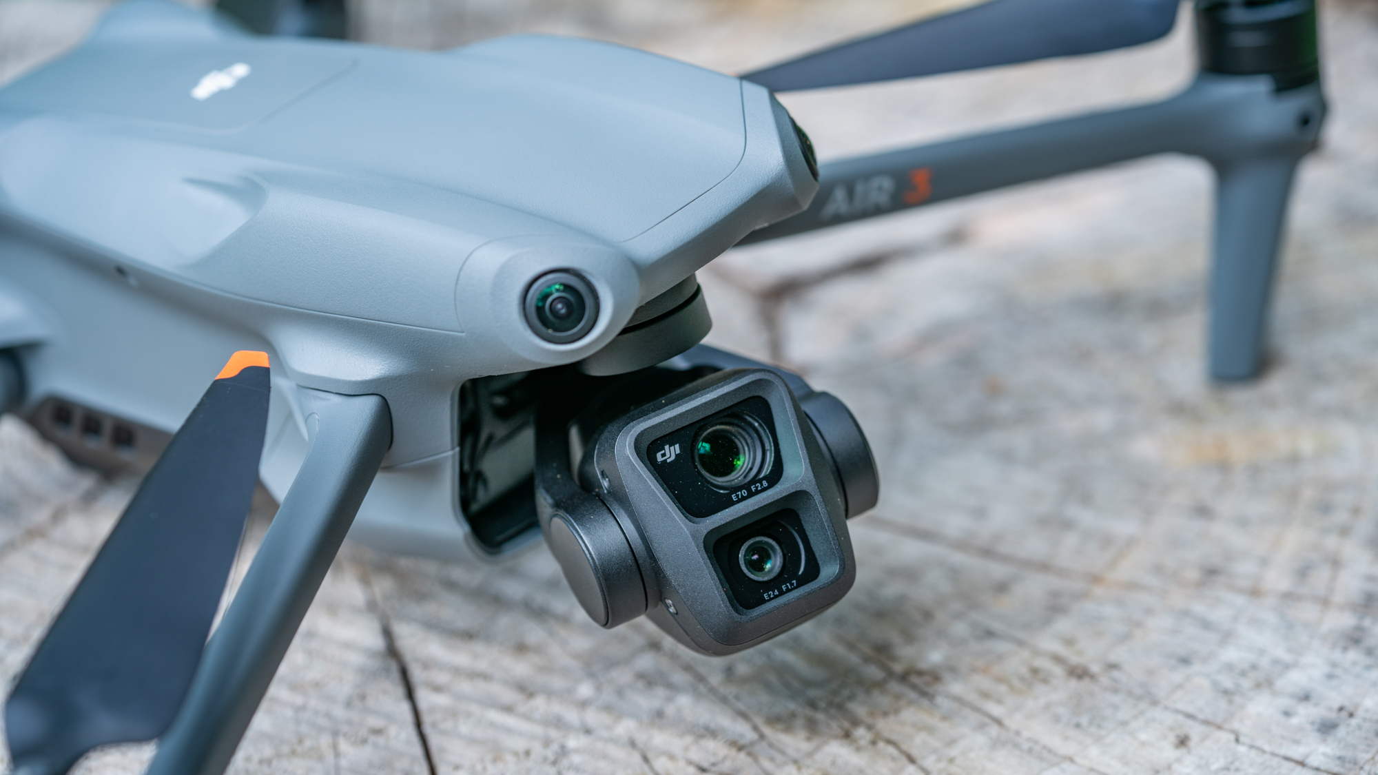 DJI Air 3 drone on a tree stump with closeup of its dual cameras