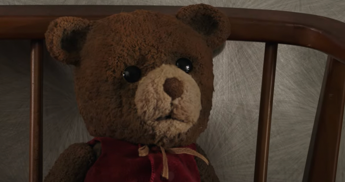 a brown teddy bear is sitting propped up in a wooden chair