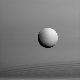 Dione hangs in front of Saturn and its icy rings in this view, captured during Cassini's final close flyby of the icy moon. North on Dione is up. The image was obtained in visible light with the Cassini spacecraft wide-angle camera on Aug. 17, 2015.