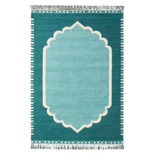 A teal rectangular rug with a baby blue medallion in the center and small white fringes