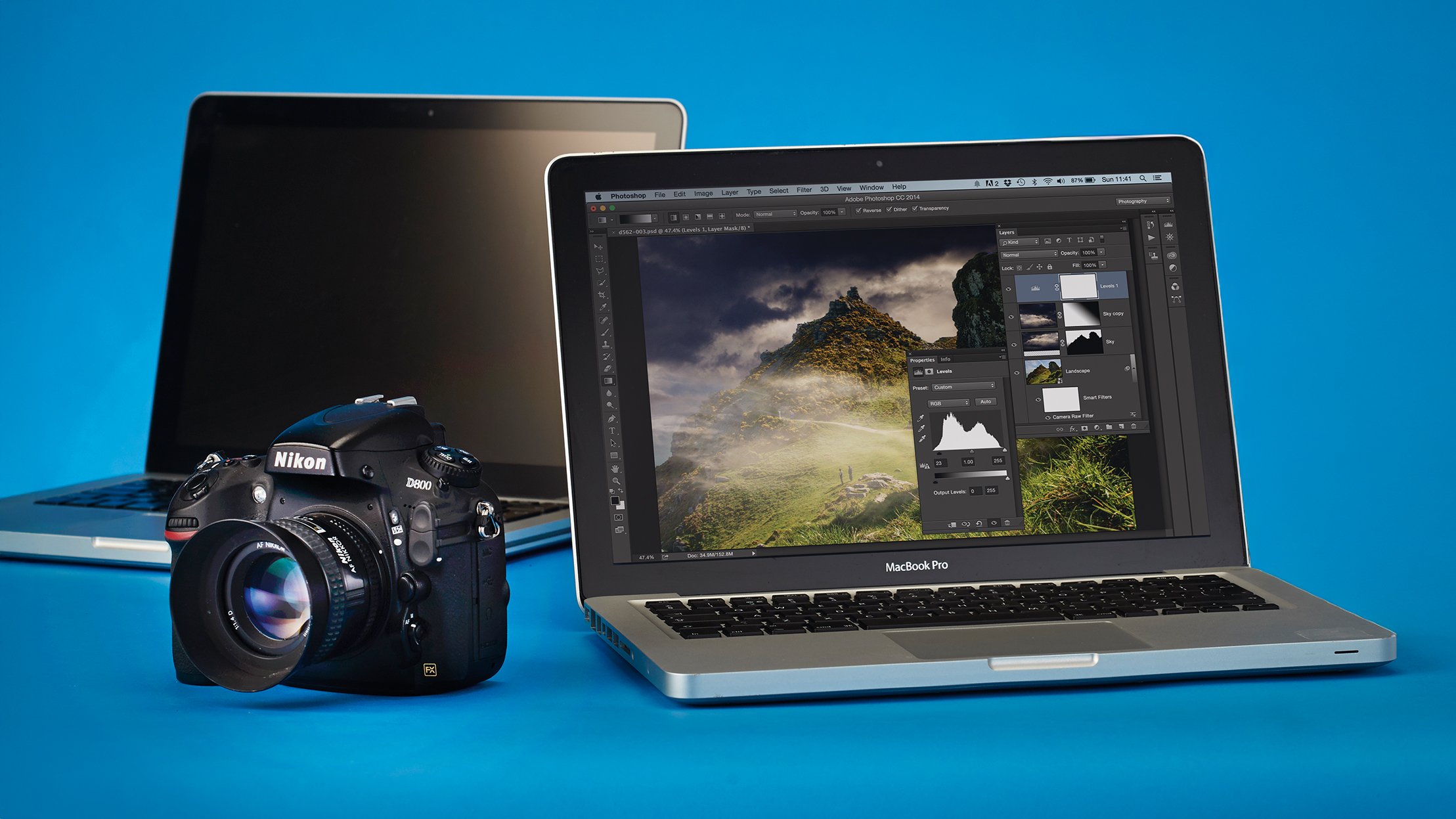 Nikon D800 next to a pair of MacBook Pro laptops, against a blue background