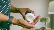 A person, wearing a fitness tracker, pouring vitamins into her hand