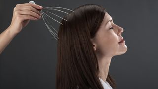 Best handheld massagers: a woman enjoys a head massage from a handheld scalp massager tool