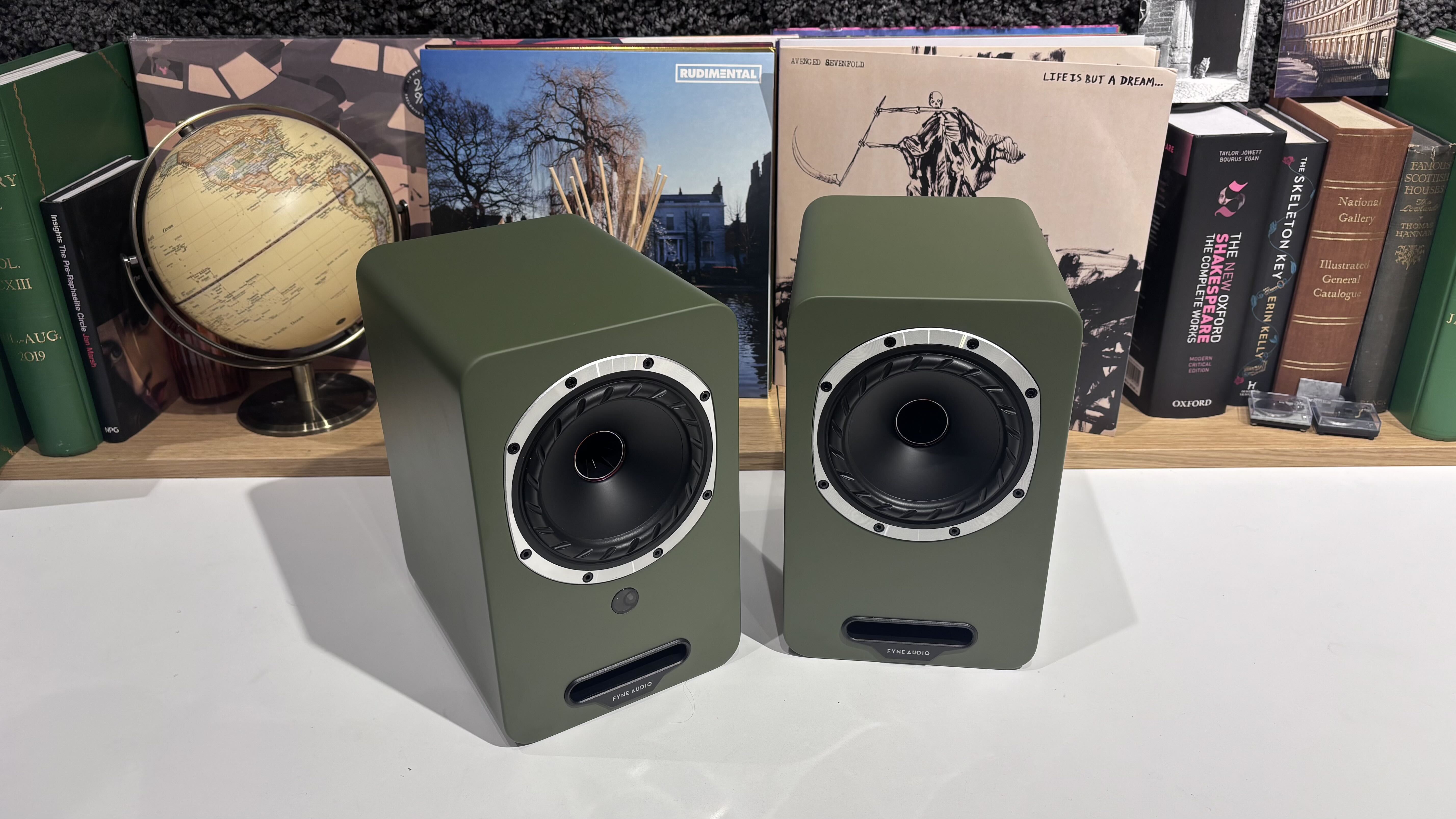 Fyne Audio Cubitt 5 speakers in olive green finish, placed on white table with records in background