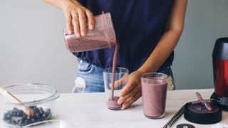 woman making a berry smoothie for breakfast
