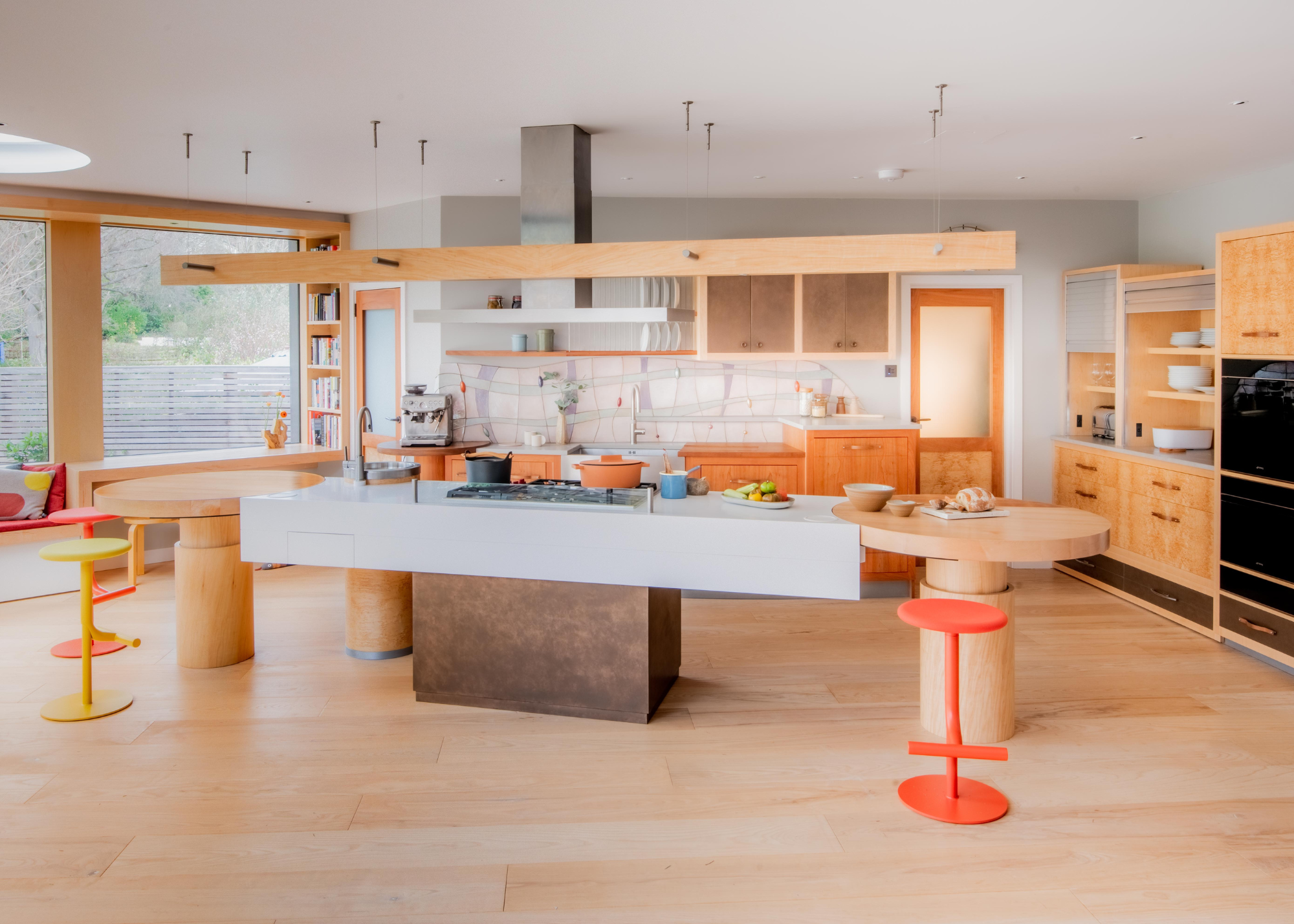 Large open plan kitchen with a central island on a bronze plinth with two wooden circular additions on either side