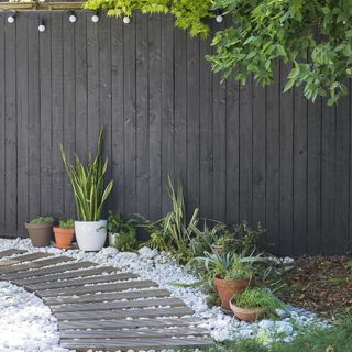 garden with grey fence and gravel and wooden slat pathway