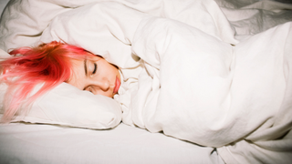A teenager with pink hair sleeps