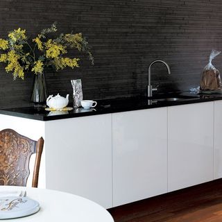 kitchen with grey wall white cabinet black counter
