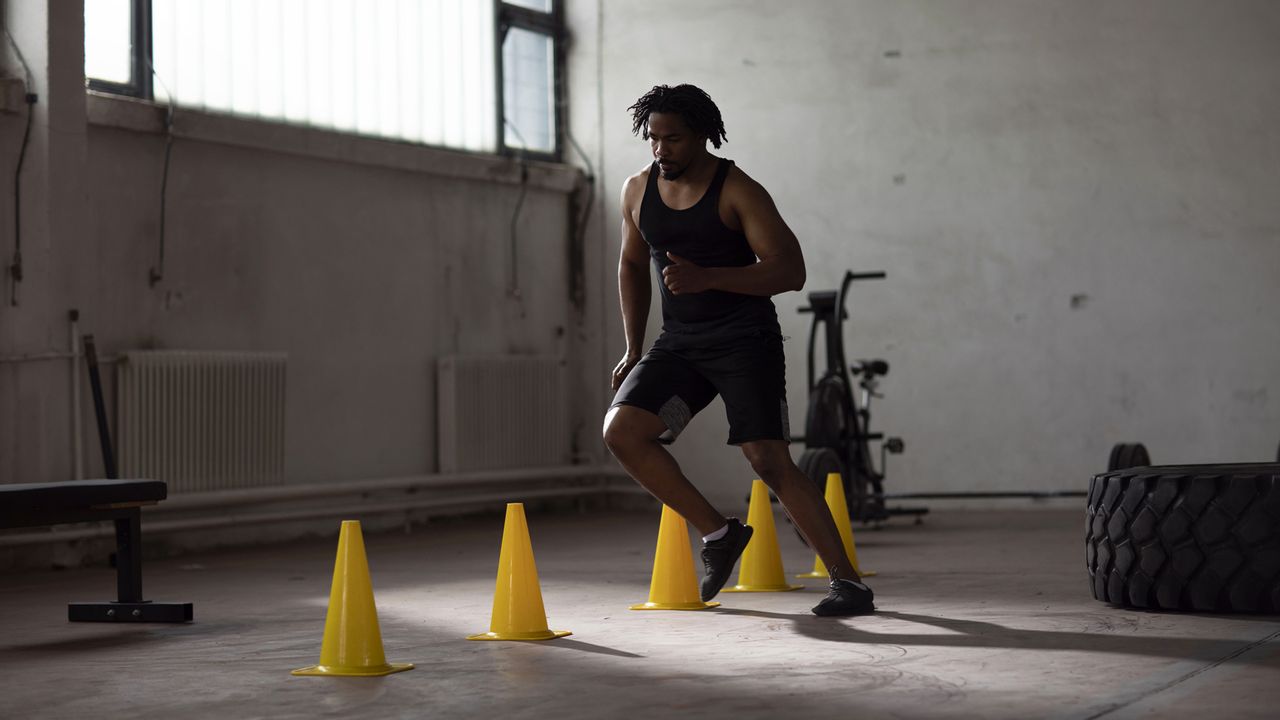 Sporty young man working on his footwork by doing drills in the gym