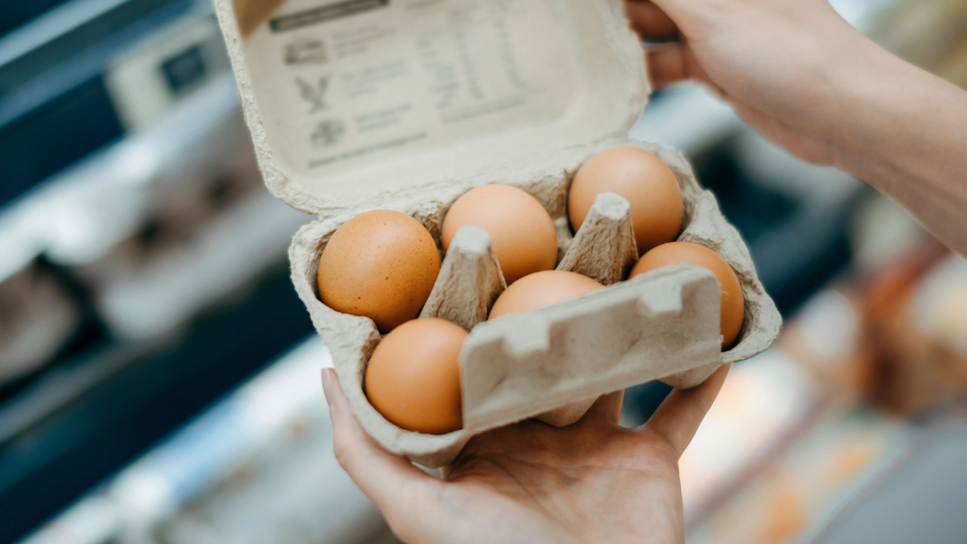 Woman's hands opening cardboard box of eggs