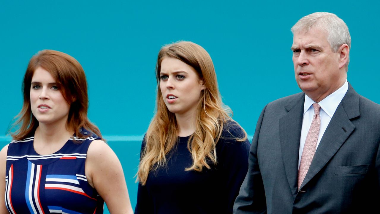 Princess Eugenie and Princess Beatrice wear striped dresses as they walk with their father Prince Andrew, who is wearing a dark suit with a pink tie