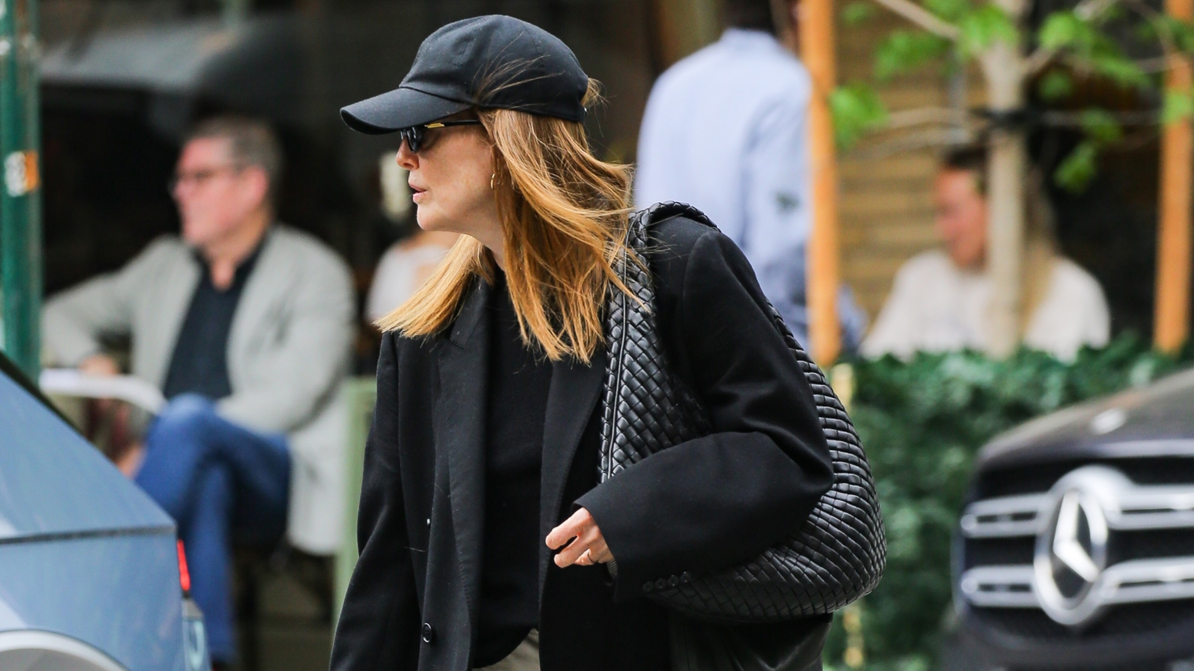 Julianne moore wears a baseball cap with an oversize blazer and a bottega veneta bag.